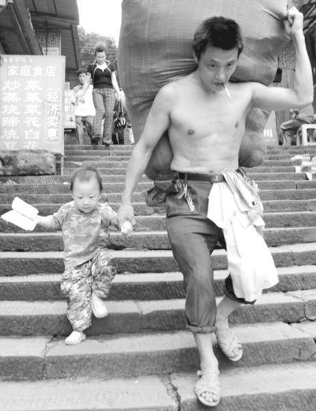 在朝天门批发市场,冉光辉(右)牵着儿子送货(2010年6月20日摄)